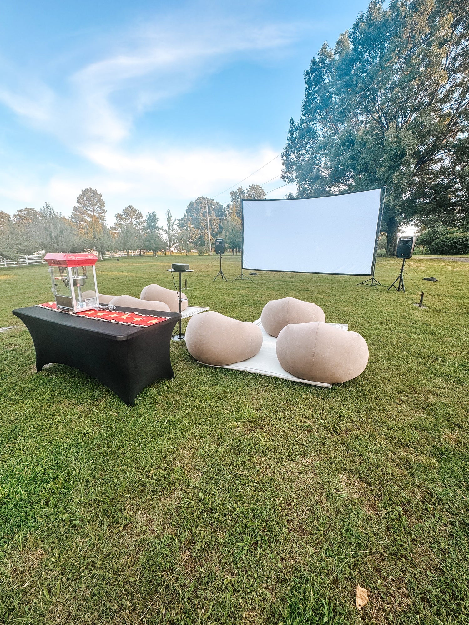 An outdoor movie setup with large screen, projector, outdoor inflatable seating, popcorn machine for rent near Tahlequah, OK
