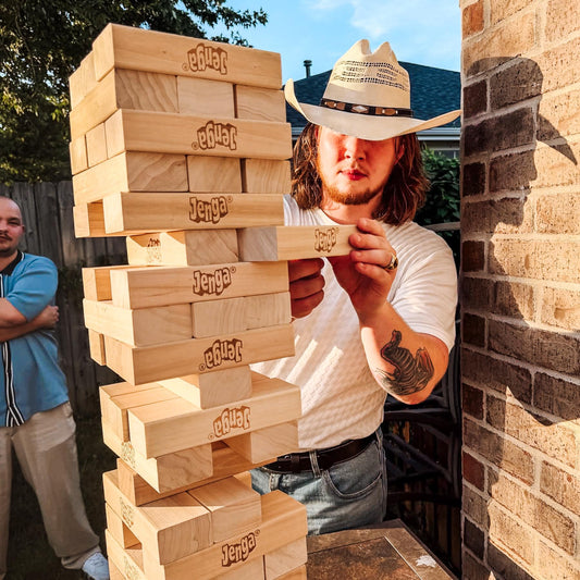 Man in cowboy hat at engagement party playing a giant jenga yard game rented near Fayetteville, AR